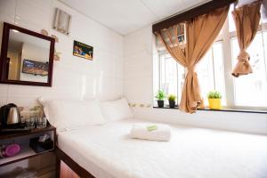 香港安逸宾馆的一间小卧室,配有一张白色的床和窗户