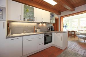 阿伦斯霍普Fachwerkhaus的厨房配有白色橱柜和炉灶烤箱。