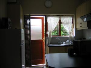 开普敦Malleson Garden Cottage的厨房设有门、水槽和冰箱
