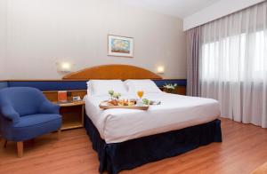 马德里阿古玛酒店的酒店客房,配有一张床和一张蓝色椅子
