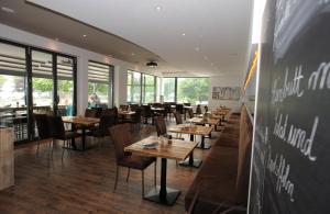 施特兰德ACQUA斯特昂德餐厅及游艇酒店的餐厅设有木桌、椅子和窗户。
