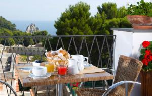 卡普里Hotel La Tosca的阳台上配有带早餐食品的木桌