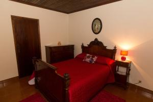 Porto JudeuCasa do Galante的卧室配有红色的床和墙上的时钟