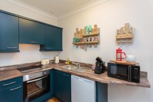 莱瑟姆-圣安妮Beach Hideaway的厨房配有蓝色橱柜和带微波炉的台面。