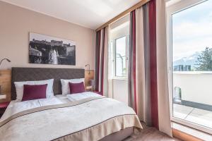 萨尔茨堡Hotel Max 70的一间卧室设有一张大床和一个大窗户