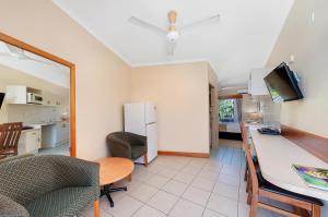 凯恩斯热带昆士兰酒店的厨房以及带桌子和冰箱的客厅。