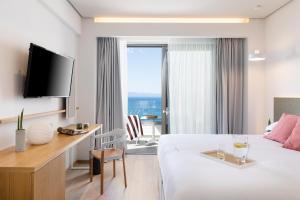 卡拉马塔Messinian Icon Hotel & Suites的酒店客房设有一张床、一张书桌和一台电视机。