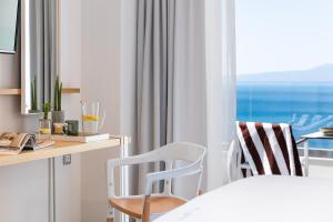 卡拉马塔Messinian Icon Hotel & Suites的一间卧室配有书桌、两把椅子和窗户。