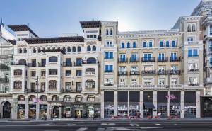 马德里Catalonia Gran Vía Madrid的白色的大建筑,街道上设有蓝色窗户