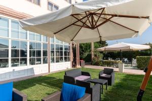 圣马尔蒂诺博纳尔贝尔戈Hotel Catullo的庭院配有桌椅和遮阳伞。