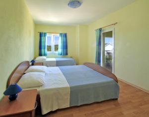 洛维什特Apartments Đuričić的一间卧室配有两张带蓝色窗帘的床和一张桌子