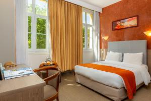 阿维尼翁科利雅得阿维尼翁万国宫大殿酒店的酒店客房设有一张床、一张书桌和窗户。