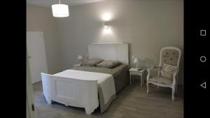 MauléonGITE IZALIN AVEC SPA A 20 min du Puy du Fou的卧室配有白色的床和椅子