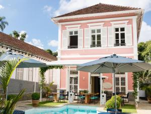 彼得罗波利斯Casa Rosa Hotel Boutique的粉红色的房子,设有游泳池和两把遮阳伞