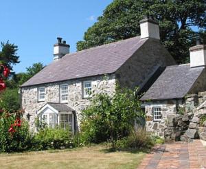 LlandegfanCoed y Berclas cottage, private orchard with stunning views的一座带石板屋顶的古老石屋