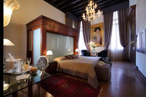 威尼斯利亚斯迪皇宫酒店的一间卧室配有一张床、一张桌子和一个吊灯。