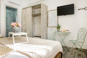 依诺罗达Meltemi luxury apartments的一间卧室配有一张床、两把椅子和一台电视