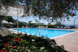 阿西西Hotel La Terrazza RESTAURANT & SPA的游泳池配有椅子、遮阳伞和鲜花