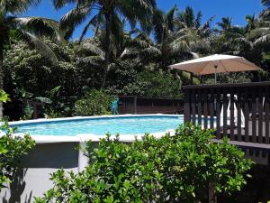 拉罗汤加JJ's Retreat的一个带遮阳伞和棕榈树的游泳池