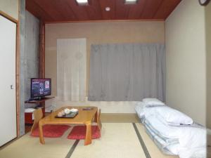 北九州浅野酒店的配有床、桌子和电视的房间