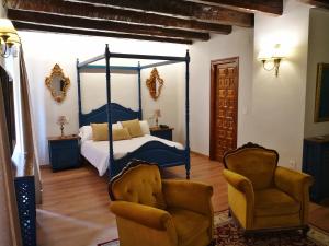 阿维拉莫哈拉兹宫酒店的一间卧室配有一张天蓬床和两把椅子