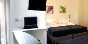 布尔戈斯艾库阿乐旅馆的一间设有床铺和笔记本电脑的房间