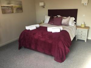 WorminghallThe Clifden Arms B&B的一间卧室配有一张大床,提供紫色床单和枕头