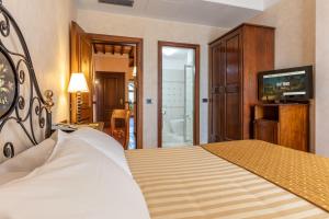 马利亚诺萨比纳Hotel Ristorante La Pergola的一间卧室配有一张床、一台电视和一间浴室。