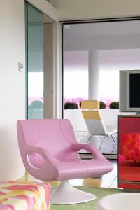 雅典塞米勒米斯酒店的客厅设有一张粉红色的椅子,配有电视