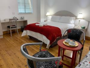博福特西Savoy Hotel Beaufort-West的一间卧室配有一张带红色毯子和桌子的床。