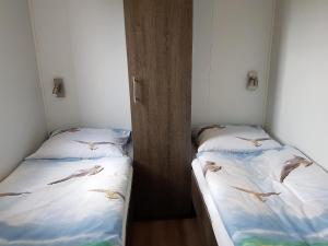 塞罗斯凯尔克Olmenduin Chalet Veere Zeeland的两张床,房间之间有鸟飞