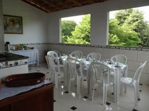 卡舒埃拉保利斯塔Casa & Hospedagem Carol的一间带桌子和白色椅子的用餐室