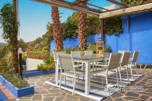 奥利维拉Villa Charma with private pool and Air conditioning close to sitges in peaceful location的一个带蓝色墙壁的庭院内的白色桌子和椅子