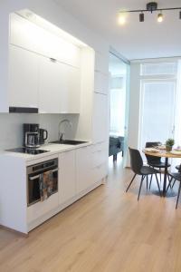罗瓦涅米Forenom Serviced Apartments Rovaniemi Valtakatu的厨房配有白色橱柜和桌椅
