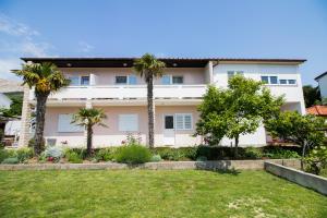 巴斯卡Rooms & Apartment Albina的一座大白色房子,在院子里种有棕榈树