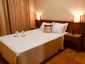 波尔图波尔蒂纳酒店的卧室配有一张带白色床单和枕头的大床。