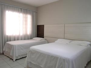 库里提巴Hotel Curitiba Campo Comprido的配有窗户的酒店客房内的两张床