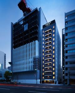 广岛Nest Hotel Hiroshima Hatchobori的一座高大的建筑,城市里灯火通明