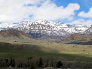 麋鹿城Mountain Man Cabin的覆盖着雪的山脉,有绿色的田野