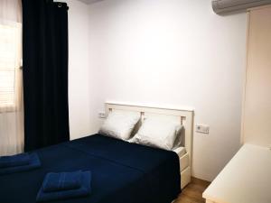 马拉加SunnySpainHolidays Apartments的一间卧室配有一张带蓝色床单和白色枕头的床。