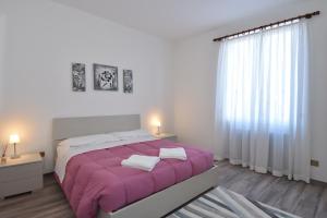 贝拉吉奥粉红之家公寓酒店的一间卧室配有一张大床和紫色毯子