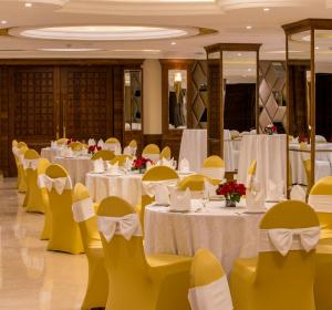 钱德加尔Regenta Central Cassia Zirakpur Chandigarh的宴会厅配有白色的桌子和黄色的椅子