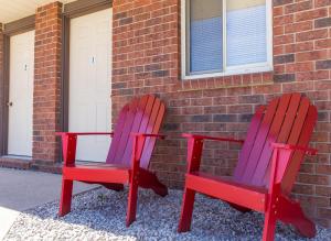 莱昂斯黑德Bear Tracks Inn的两把红紫色椅子坐在砖砌建筑旁边