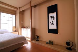 东京TOMARU MORISITA HOUSE的卧室配有一张床,墙上挂着一幅画