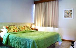 伊列乌斯Pousada Pier do Pontal的一间卧室设有一张绿色的床和一个窗户。