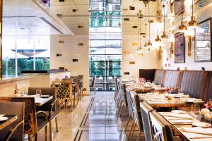 迪拜塔马尼码头酒店及公寓的餐厅设有木桌、椅子和窗户。