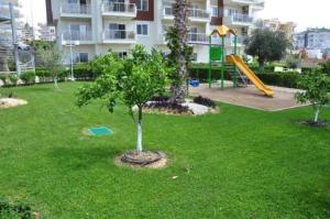 阿萨拉尔Apartment的公园,公园内有带树和滑梯的游乐场