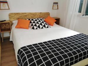 科孚镇Lilliput Studio Corfu Old Town的一间卧室配有黑色和白色的床以及橙色枕头。