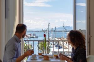 卡利亚里Hotel Aristeo的坐在桌子上,欣赏海港景色的男人和女人