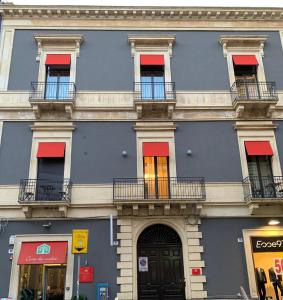 卡塔尼亚Corte dei medici - Palace的蓝色的建筑,设有红色的窗户和阳台